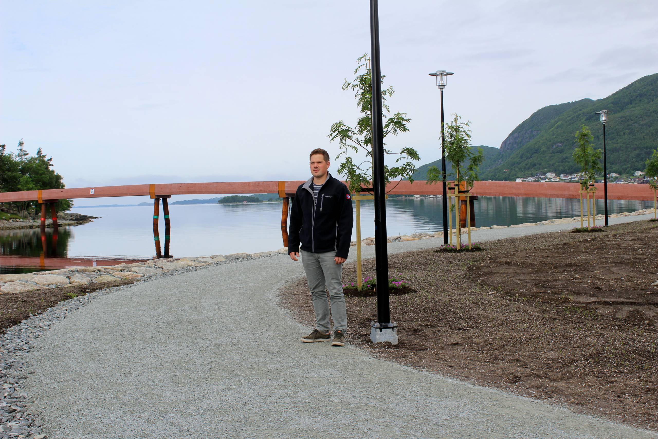 Sigurd Slåtto viser stolt frem den ferdige turstien. Staalverksbruå i bakgrunnen.